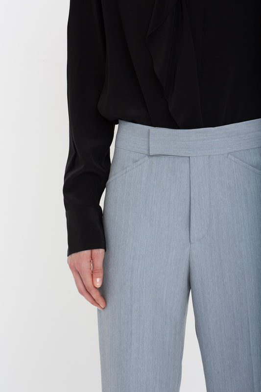 Close-up of a person wearing a black long-sleeve blouse and Victoria Beckham trousers in light grey. The focus is on the bottom half of the blouse and top part of the Victoria Beckham Exclusive Wide Cropped Flare Trouser In Marina.