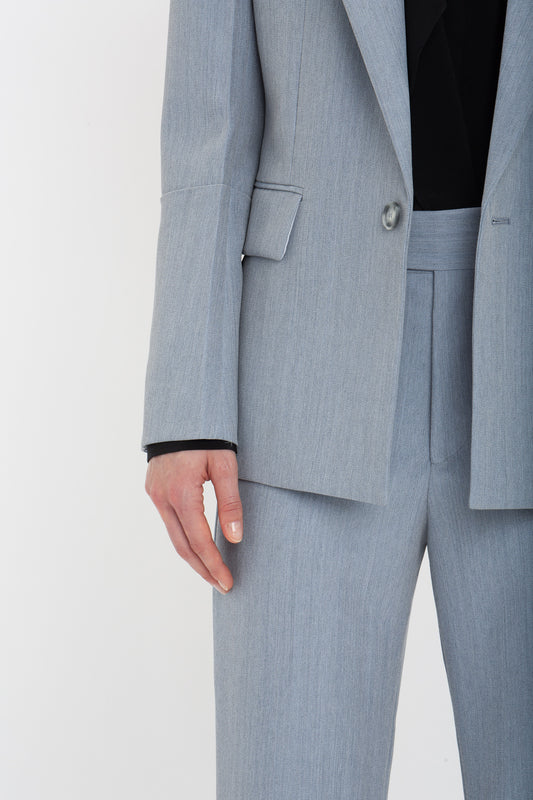 Person in a gray, impeccably tailored Victoria Beckham Exclusive Sleeve Detail Patch Pocket Jacket In Marina with their left hand visible, against a plain white background.