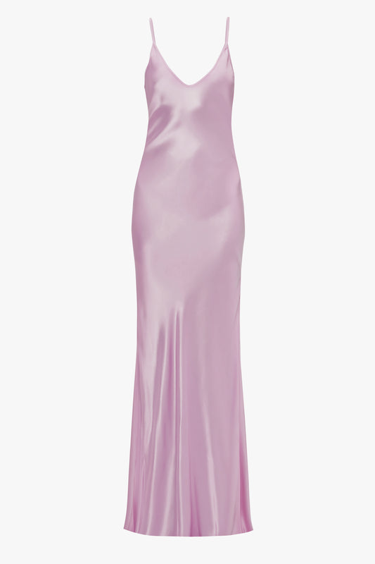 A long, silky, light pink Low Back Cami Floor-Length Dress In Rosa with spaghetti straps and a fitted form, reminiscent of the elegance seen in Victoria Beckham's designs.
