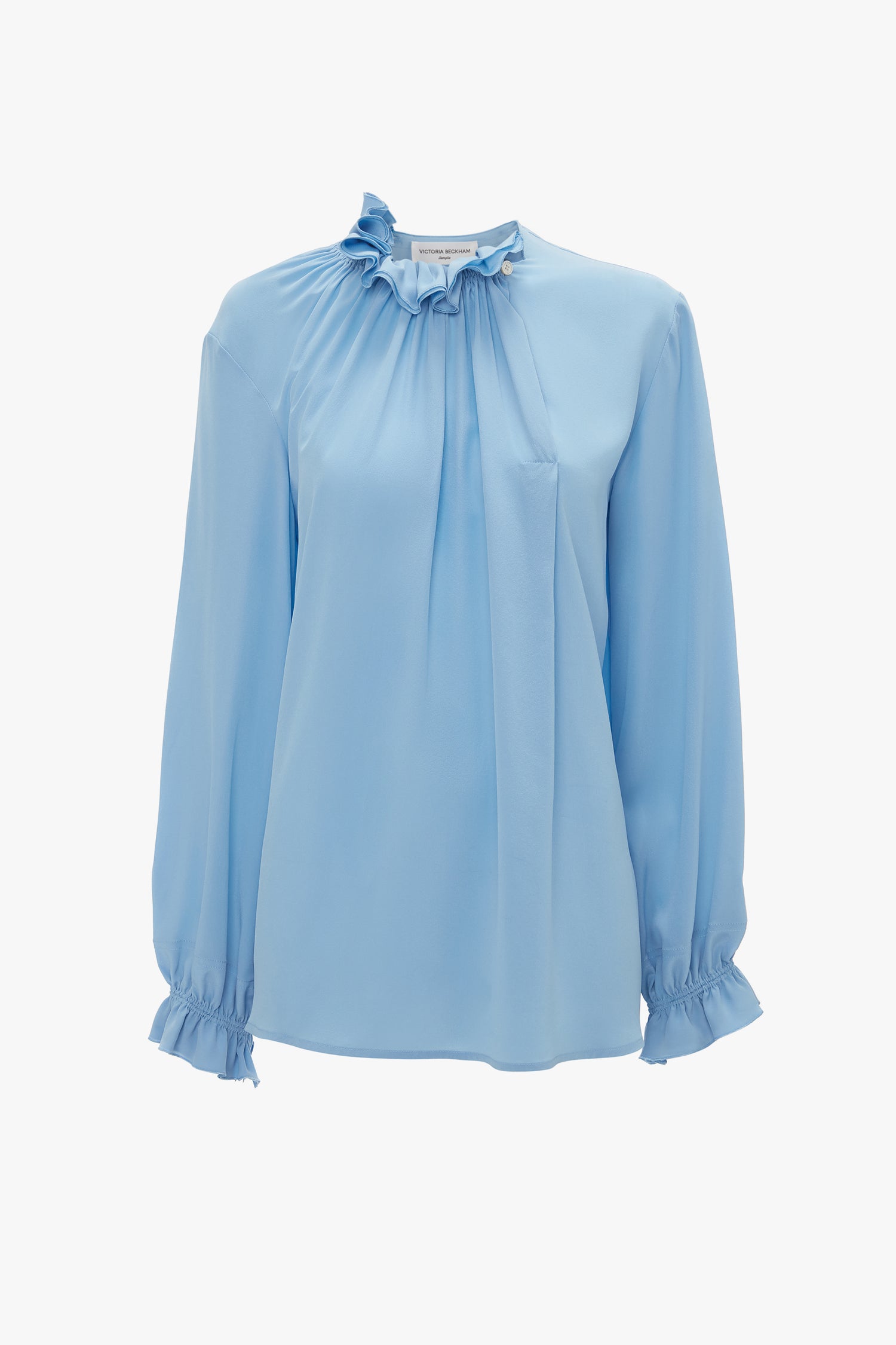 A cornflower blue, long-sleeved crepe de chine blouse with a gathered neckline and ruffled cuffs against a white background. Product: Exclusive Ruffle Neck Blouse In Cornflower Blue by Victoria Beckham.