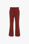 A pair of Victoria Beckham Wide Cropped Flare Trouser In Russet, featuring a tailored waistband and front pockets. These 1970s-inspired trousers add a retro chic vibe to any outfit.