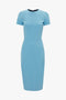 A knee-length, short-sleeved, periwinkle blue dress with a fitted waist and a high neckline, reminiscent of an Exclusive Fitted T-Shirt Dress In Periwinkle Blue by Victoria Beckham.