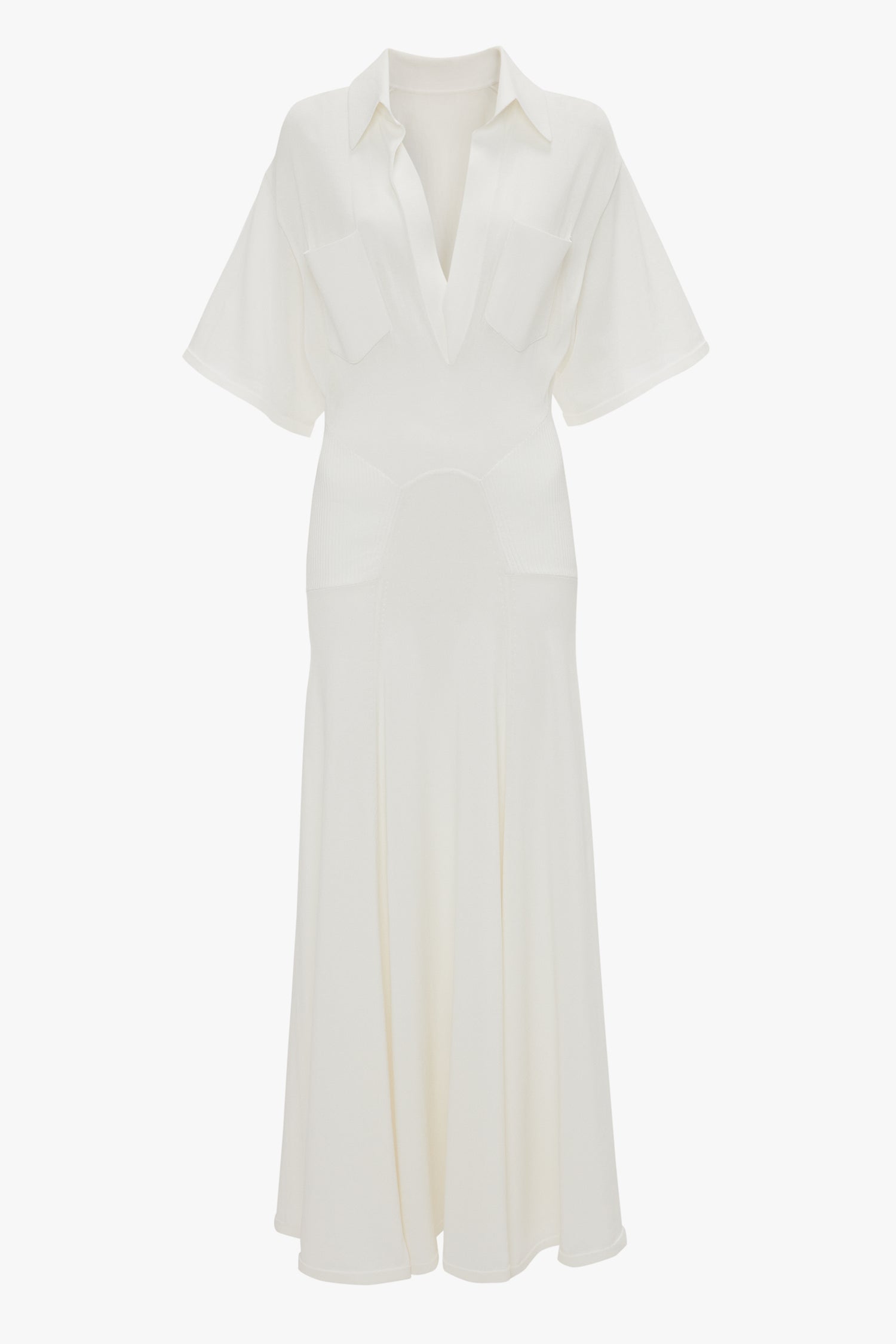 A white, short-sleeved, collared dress with a flared skirt and two front pockets exuding relaxed glamour. The "Panelled Knit Dress In White" by Victoria Beckham is made from fine-gauge knit for that perfect blend of comfort and style.