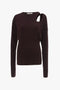 A long-sleeved, dark brown Twist Detail Jersey Top In Deep Mahogany from Victoria Beckham with a unique cut-out design near the right shoulder, exuding casual sophistication.