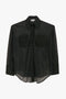 A Pocket Detail Shirt In Black by Victoria Beckham is a fine-gauge knit translucent black button-up shirt with long sleeves, a collar, and two chest pockets.