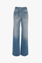 Wide-leg blue denim jeans with front pockets and a high waist. The Alina High Waisted Jean In Light Summer Wash by Victoria Beckham features vintage denim that is lightly faded for a slightly worn look.