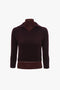 A dark brown, long-sleeved ribbed sweater with a V-shaped neckline and a fold-over collar crafted from mid-weight merino wool, exhibited on a mannequin, is the Double Layer Top In Deep Mahogany by Victoria Beckham.