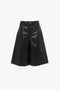 Leather Bermuda Short In Black by Victoria Beckham with a high waist, a button and zipper closure at the front, and knee-length wide legs, offering a flattering silhouette.