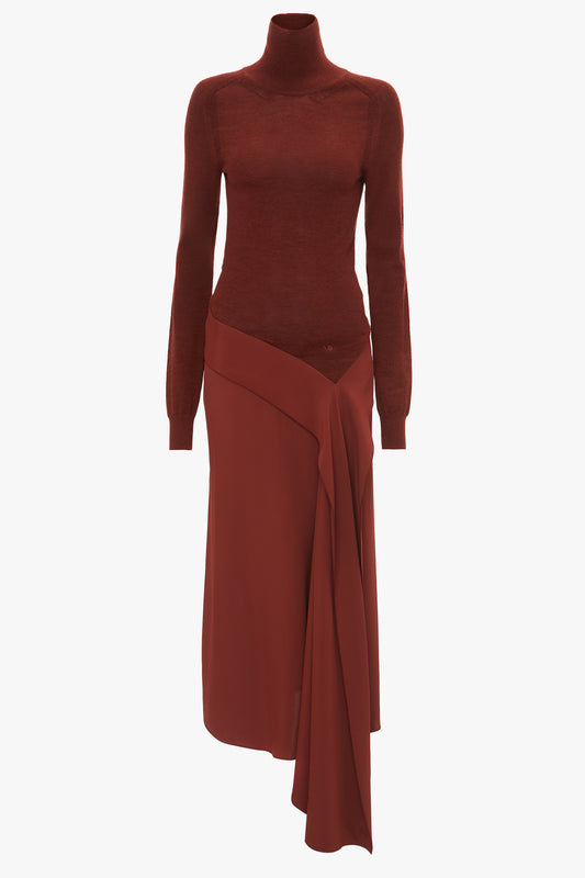 A rust-colored turtleneck sweater paired with a matching asymmetrical wrap skirt. The outfit has a fall-inspired, monochromatic design reminiscent of Victoria Beckham's High Neck Tie Detail Dress In Russet.