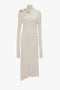 A **Long Sleeve Cut-Out Jersey Midi Dress In Bone** by **Victoria Beckham** features split sleeves, cut-out details on the shoulder and chest, an asymmetric hemline, and designed stitching on the side.