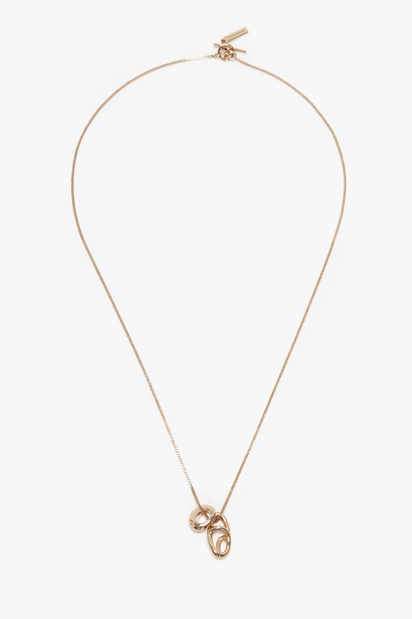 An exquisitely crafted in Italy, light gold necklace, the Exclusive Abstract Charm Necklace In Light Gold by Victoria Beckham, features a thin chain and two interlocking circular pendants, offering an abstract charm to any ensemble.