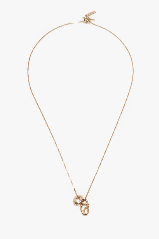 An exquisitely crafted in Italy, light gold necklace, the Exclusive Abstract Charm Necklace In Light Gold by Victoria Beckham, features a thin chain and two interlocking circular pendants, offering an abstract charm to any ensemble.