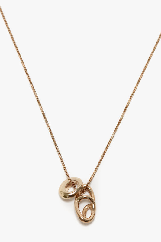 An Exclusive Absract Charm Necklace In Light Gold with a thin chain and three interlocking rings as a pendant, exquisitely crafted in Italy by Victoria Beckham.