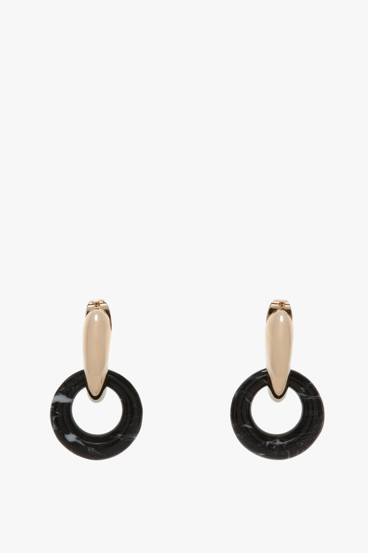 A pair of Exclusive Resin Pendant Earrings In Light Gold-Black by Victoria Beckham, with gold-toned studs and black circular pendants, crafted from 100% brass, against a white background.