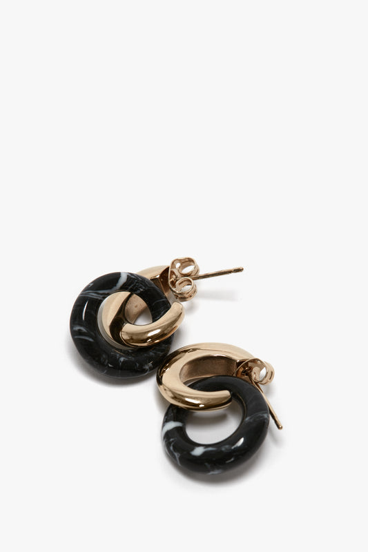 A pair of light gold and black hoop earrings with a marble-like texture on the black portion. These Exclusive Resin Pendant Earrings In Light Gold-Black by Victoria Beckham feature post and butterfly backs for fastening.