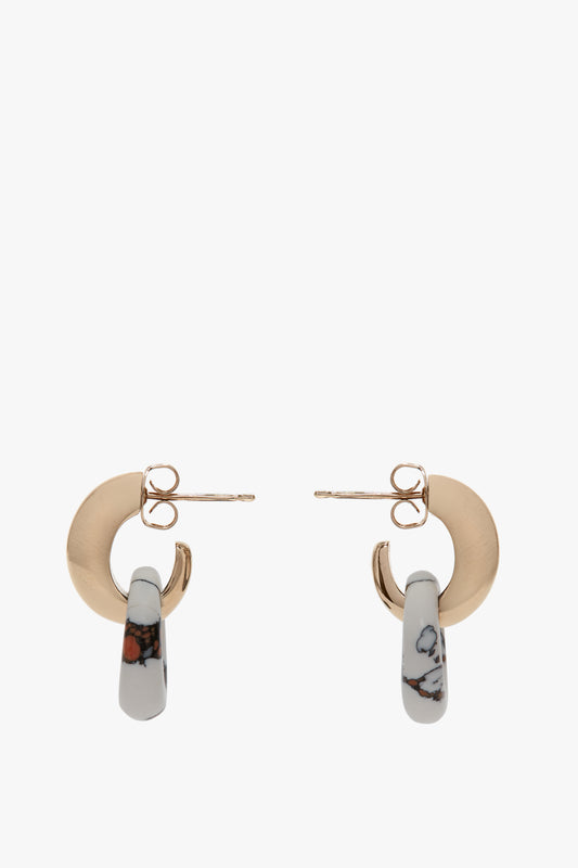 Exclusive Resin Pendant Earrings In Light Gold-White by Victoria Beckham featuring gold studs with attached marbled white and gray loops, elegantly displayed against a white background. Crafted from antiallergic stainless steel and brass, they marry style with comfort.