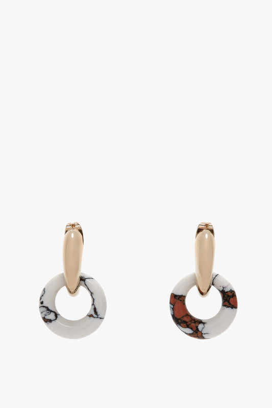 A pair of Exclusive Resin Pendant Earrings In Light Gold-White by Victoria Beckham with gold-colored oval tops and circular stone pendants, featuring white with black marble-like patterns and reddish-brown accents, crafted from antiallergic stainless steel.