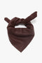 A dark brown, folded leather scarf with a knot at the top and a small embossed "VB" logo near the bottom, perfect for adding a touch of masculine tailoring to feminine separates. This is the Leather Scarf In Bordeaux by Victoria Beckham.