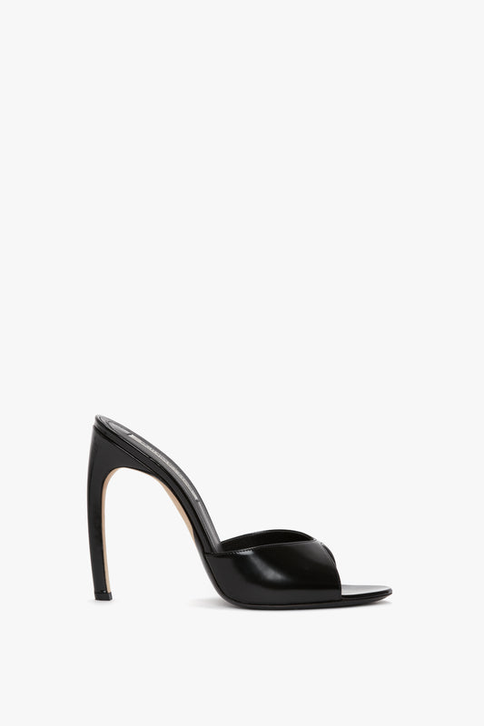 A Classic Mule In Black Calf Leather by Victoria Beckham features a seductive curved heel, open toe, and sleek stiletto design on a white background.