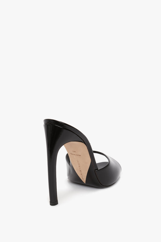 A Classic Mule In Black Calf Leather by Victoria Beckham, crafted from luxury calf leather with an open back and pointed toe, viewed from an angled rear perspective on a white background, boasts a seductive curved heel for an added touch of elegance.