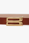 Close-up of a versatile Exclusive Micro Frame Belt In Tan Leather made from smooth calf leather, featuring a distinctive gold buckle shaped to form the letter "B" by Victoria Beckham.