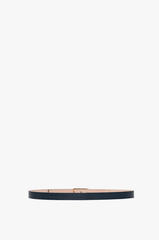 A thin, dark-colored leather belt with gold hardware and a simple buckle, laid flat on a white background.
Product Name: Frame Belt In Midnight Blue Croc Embossed Calf Leather
Brand Name: Victoria Beckham

Revised Sentence: The Victoria Beckham Frame Belt in Midnight Blue Croc Embossed Calf Leather, with gold hardware and a simple buckle, laid flat on a white background.