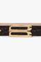 Close-up of a **Victoria Beckham Frame Belt In Espresso Croc Embossed Calf Leather**, featuring a gold double-pronged buckle set against an alligator skin texture.