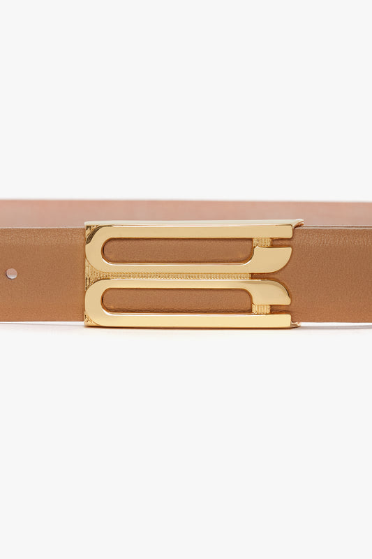 A close-up of the **Frame Belt In Camel Leather by Victoria Beckham**, crafted from smooth calf leather, featuring luxury gold hardware and a unique, modern design buckle.