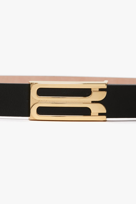 A versatile accessory, the Victoria Beckham Frame Belt In Black Leather with a gold rectangular buckle featuring two parallel cut-out lines in the center is a wardrobe classic.