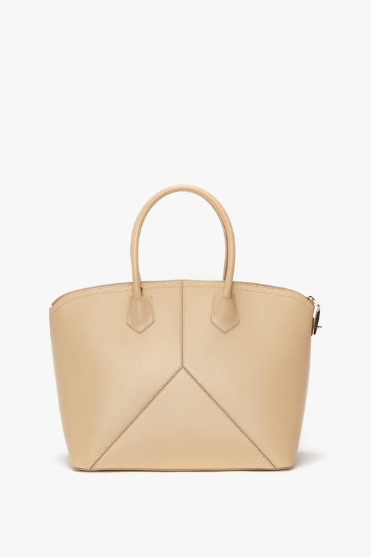 The Victoria Beckham Victoria Bag In Sesame Leather features two short handles, a structured design, and leather panels, all set against a plain white background.