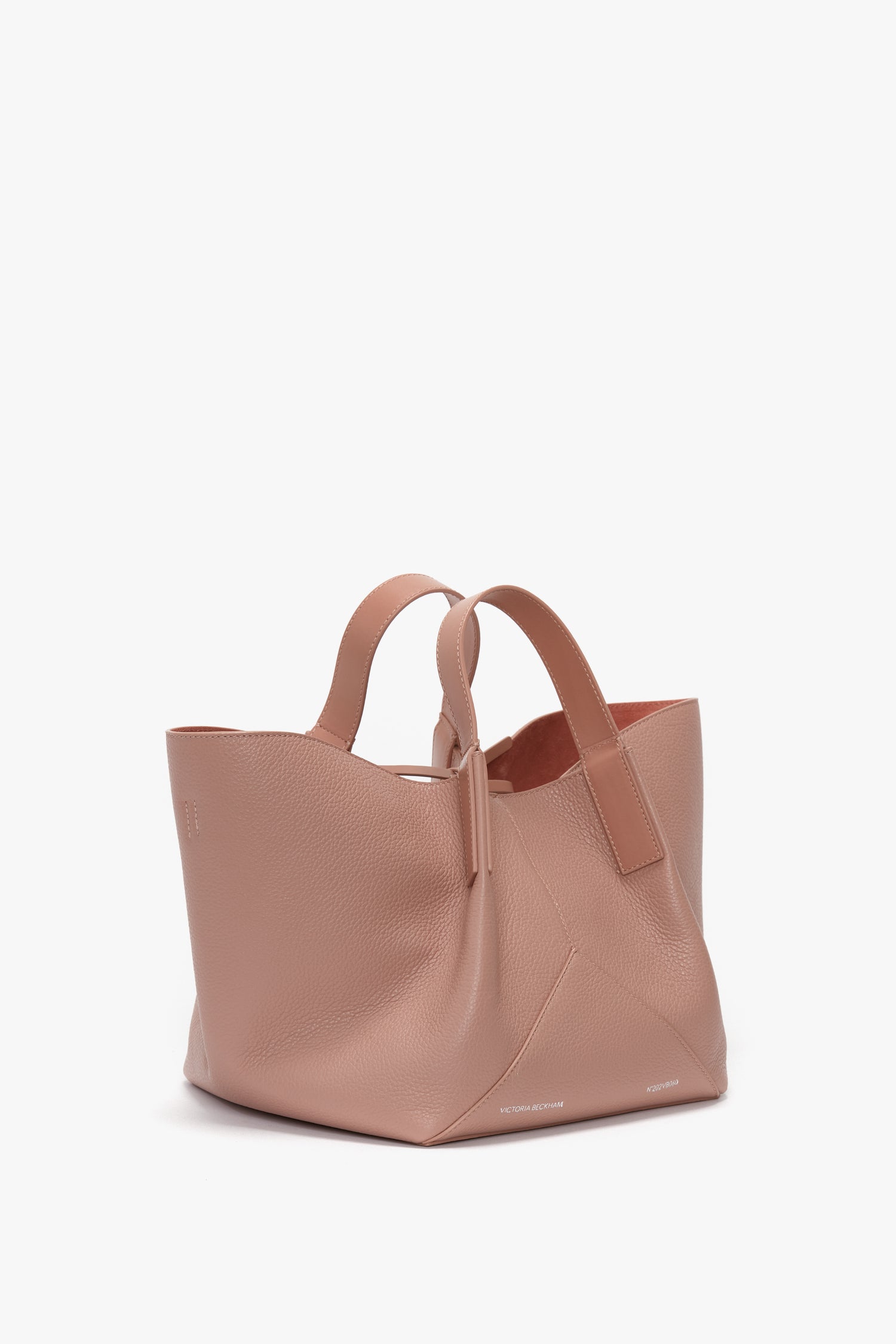 A light pink, W11 Mini Tote Bag In Marshmallow Leather by Victoria Beckham made from marshmallow-soft calf leather with a structured design and two handles, placed against a white background.