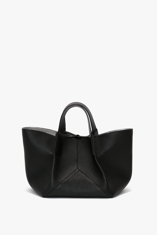 A W11 Mini Tote In Black Leather by Victoria Beckham with short leather handles and an open top, featuring a geometrically structured design that exudes luxurious sophistication.