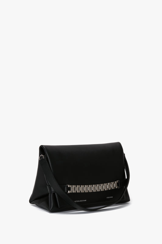 A black leather Chain Pouch Bag with Brushed Silver Chain In Black Leather by Victoria Beckham featuring a brushed silver chain detail on the front and a detachable strap.