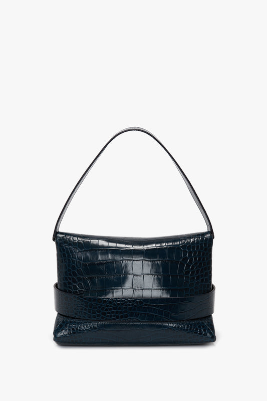 A Victoria Beckham B Pouch Bag In Croc Effect Midnight Blue Leather is displayed against a plain white background.