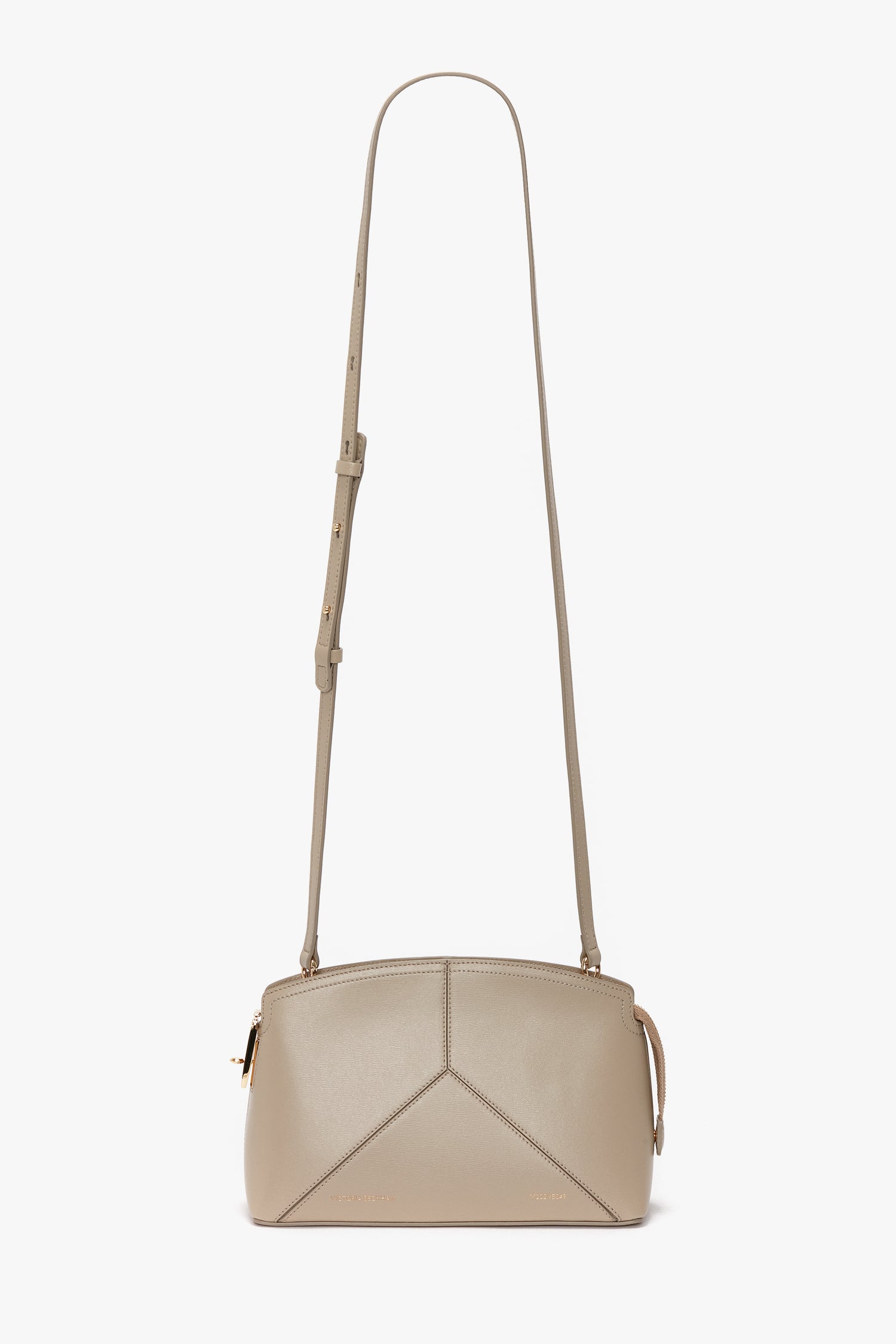 The Victoria Beckham Victoria Crossbody Bag In Taupe Leather, with a structured design, features a long adjustable strap, simple geometric stitching on the front, and gold-toned hardware. Inspired by Victoria Beckham's elegant style.