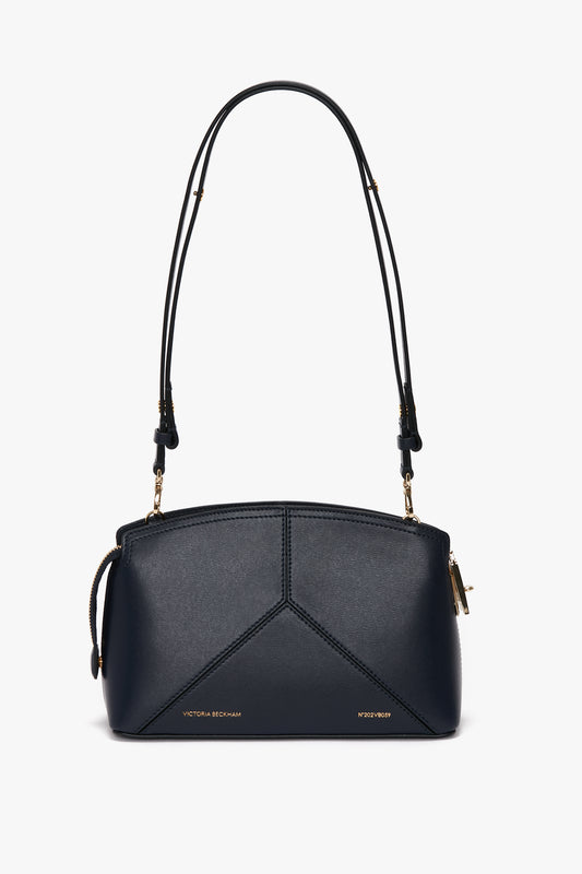 A navy leather handbag with a geometric design, dual shoulder straps, and gold hardware. Featuring a structured silhouette, the brand's name is displayed in gold text on the lower front.