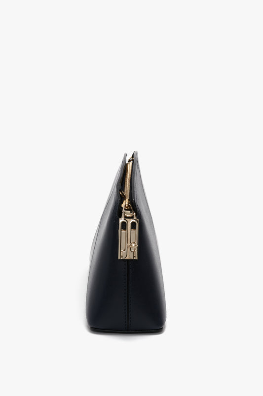 Side view of an Exclusive Victoria Crossbody Bag In Navy Leather by Victoria Beckham with a gold zipper and hardware, featuring a structured silhouette, set against a plain white background.