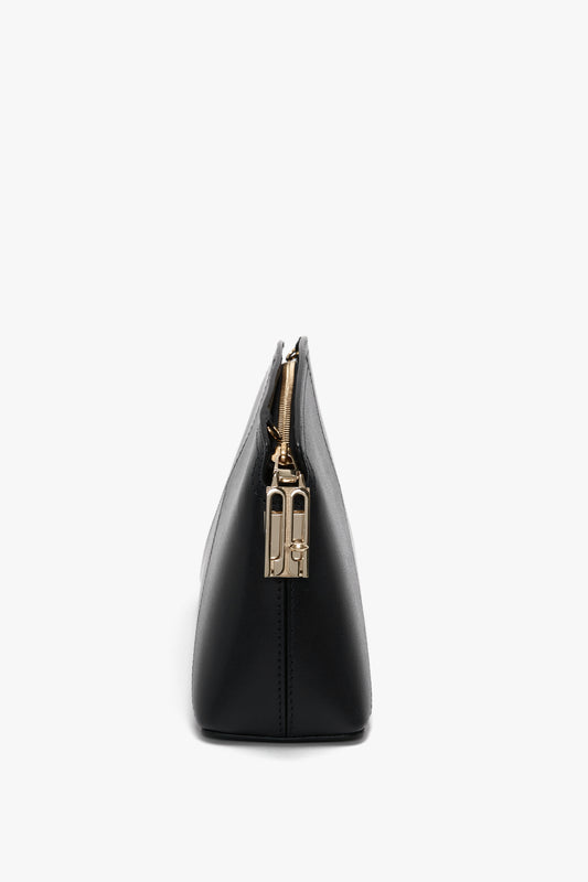 A side view of the Victoria Beckham Victoria Crossbody In Black Leather in black textured calf leather with a gold zipper and pull tab.