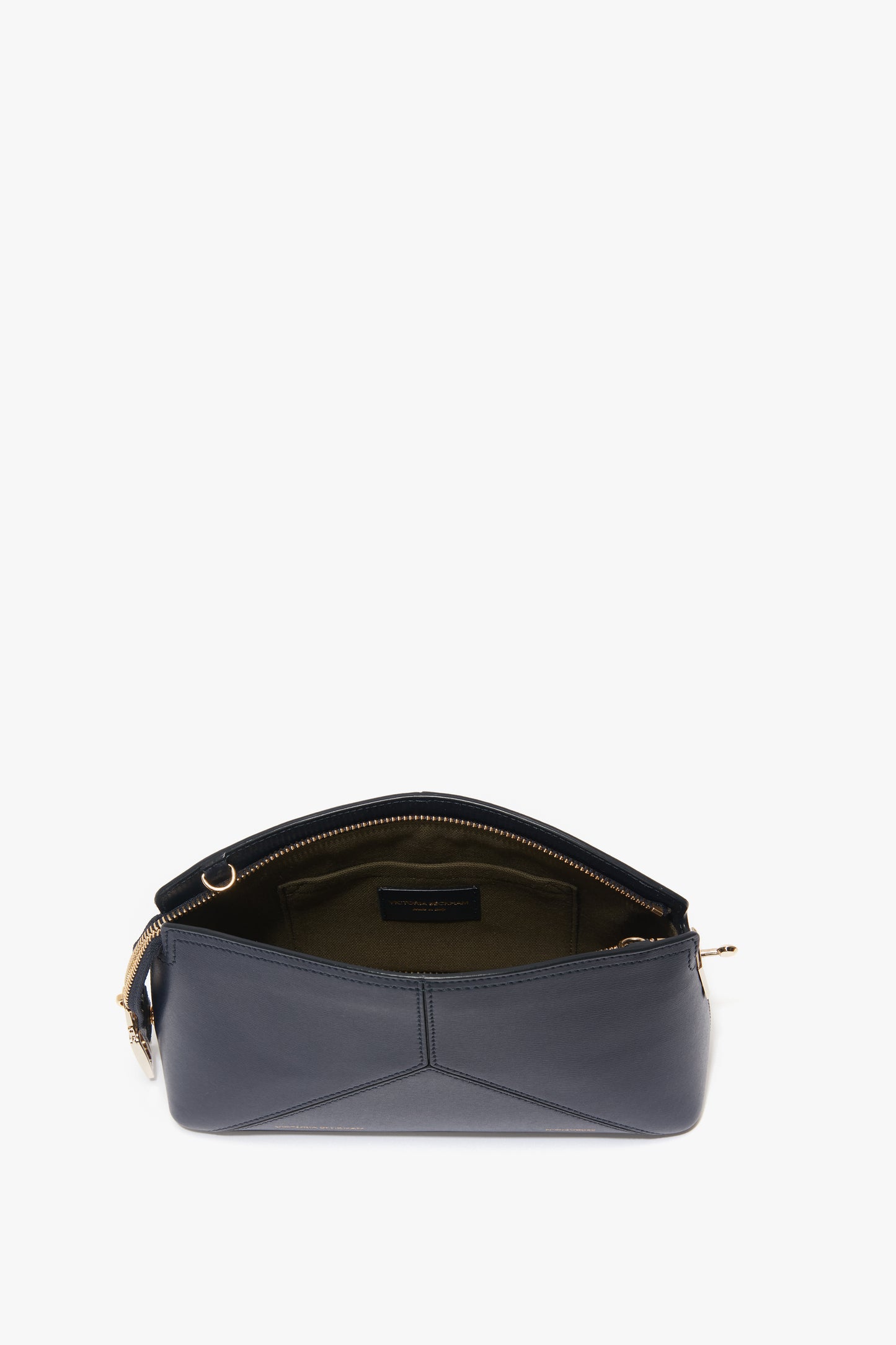 A luxuriously textured Victoria Beckham Exclusive Victoria Crossbody Bag In Navy Leather with a zippered opening and a structured silhouette reveals an empty interior lined with dark fabric.