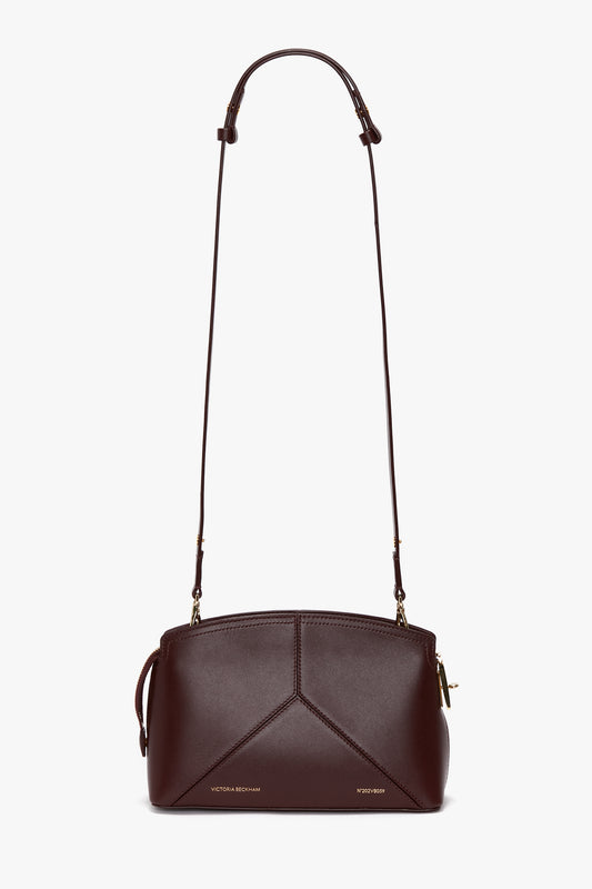 The Victoria Beckham Victoria Crossbody Bag In Burgundy Leather is crafted from premium calf leather with a minimalistic design. It features clean lines, an adjustable shoulder strap, and tiny gold-toned hardware accents that complement its structured shape. The padlock closure adds both security and style.