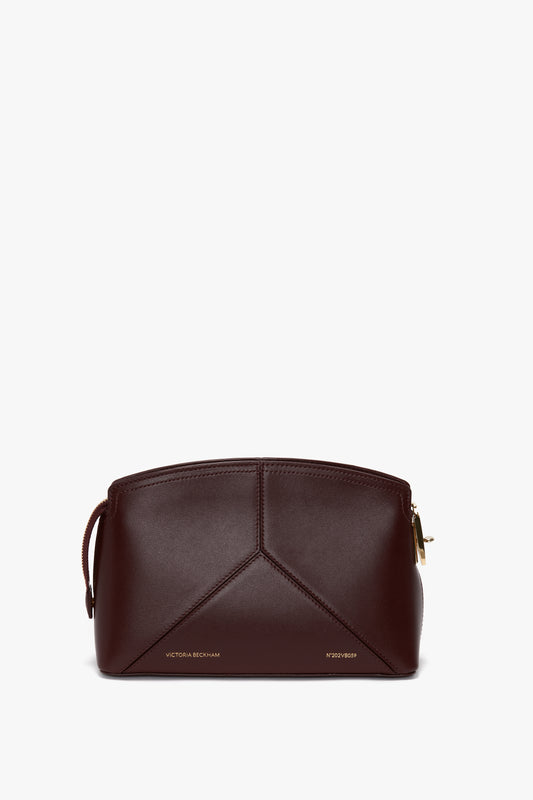 A Victoria Crossbody In Burgundy Leather by Victoria Beckham, featuring gold-tone hardware and subtle branding at the bottom.