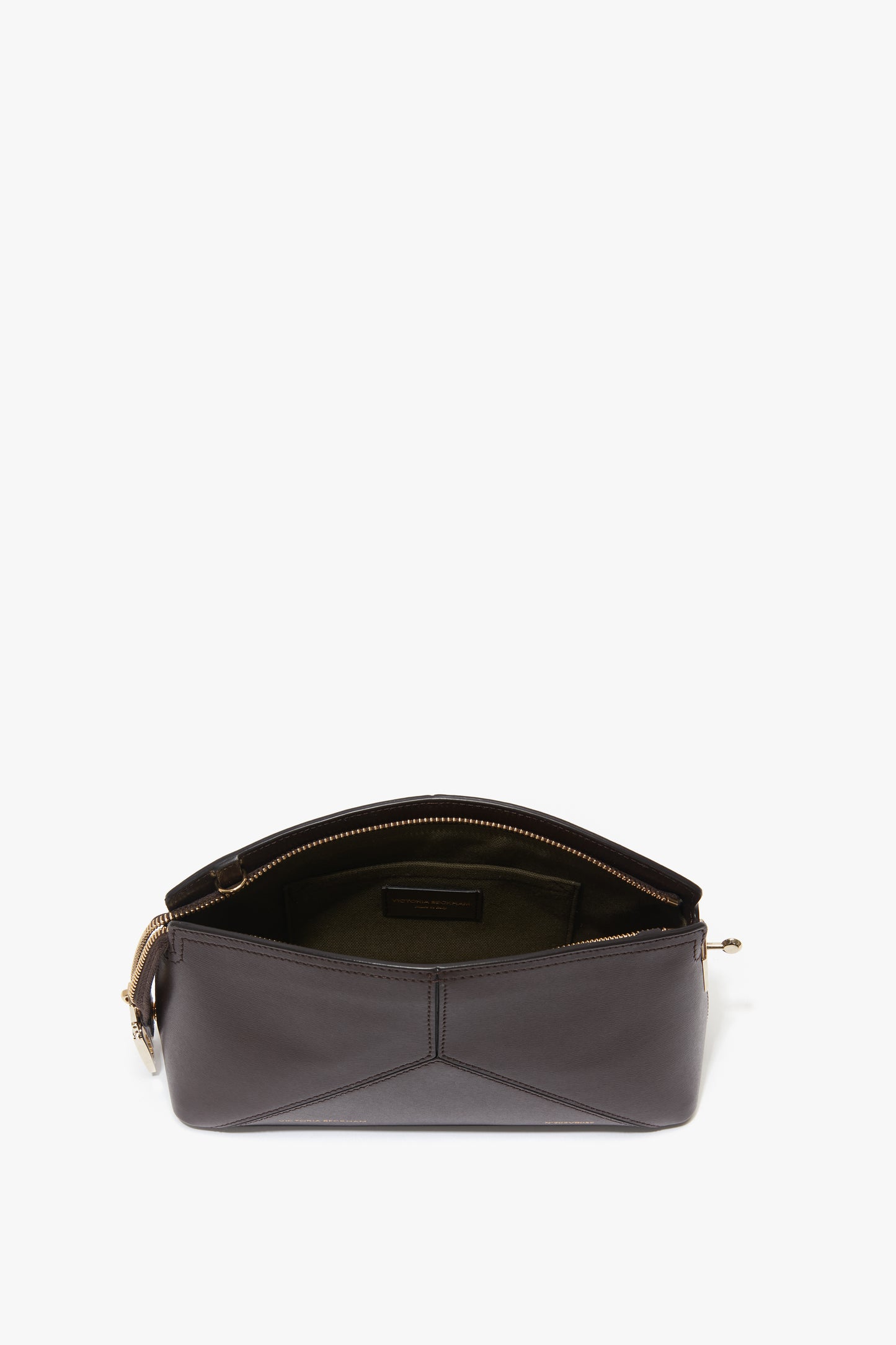 The Exclusive Victoria Crossbody Bag In Brown Leather by Victoria Beckham is a dark brown handbag crafted from premium calf leather, featuring a zipper opening that reveals a spacious interior with fabric lining and an adjustable strap for versatile wear.