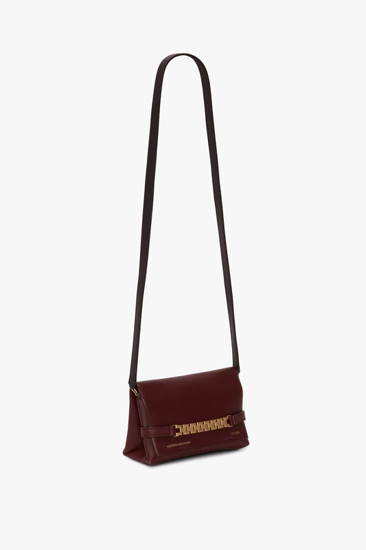 A Mini Chain Pouch Bag With Long Strap In Burgundy Leather by Victoria Beckham with a long strap and gold-tone chain detail on the flap.