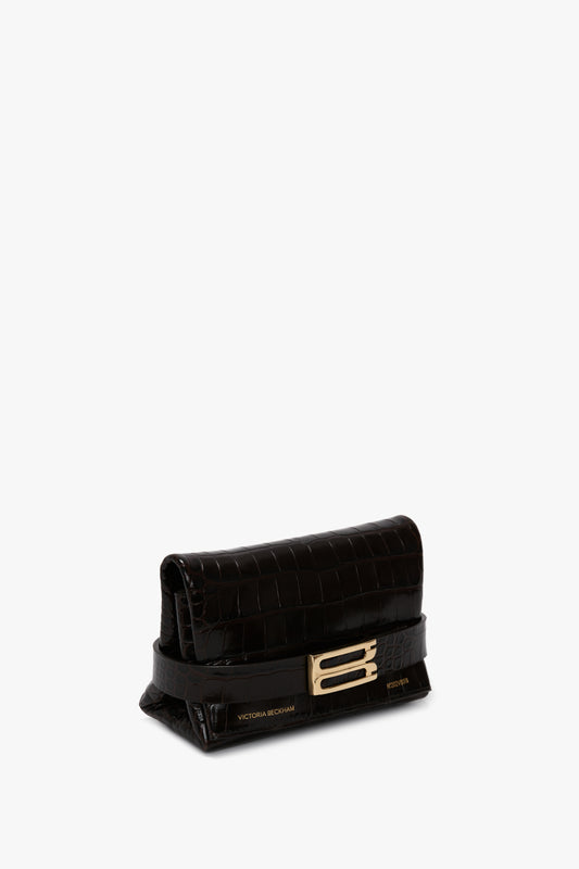 A small, black **Mini B Pouch Bag In Croc Effect Espresso Leather** by **Victoria Beckham**, with a gold buckle embellishment and a detachable crossbody strap.