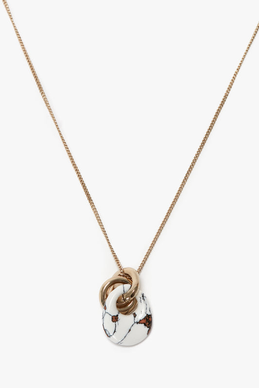 Victoria Beckham's Exclusive Resin Pendant Necklace In Light Gold-White with a 31cm-long chain and a round resin pendant featuring white marble and small dark accents intertwined with gold loops.