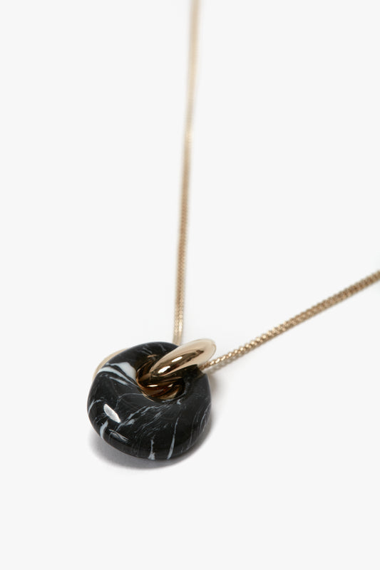 A Victoria Beckham Exclusive Resin Pendant Necklace In Light Gold-Black featuring a black and white marbled stone, paired with a small gold ring on a 100% brass chain in light gold.