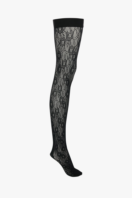 A single Exclusive VB Monogram Lace Hold-Ups In Black by Victoria Beckham with a sheer finish on a white background.