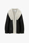 A Shearling Coat In Monochrome by Victoria Beckham, displayed against a white background, perfectly complements a cream black polo neck jumper.