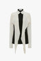 A Victoria Beckham Oversized Bow Detail Blouse In Vanilla with a black central section and white sleeves and lapels that hang down in a cape-style drape, adding a dramatic finishing touch.