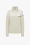 A cream-colored, long-sleeve turtleneck sweater with ribbed texture and a black accent line across the chest, this Collar Detail Jumper In Natural from Victoria Beckham exudes casual sophistication.